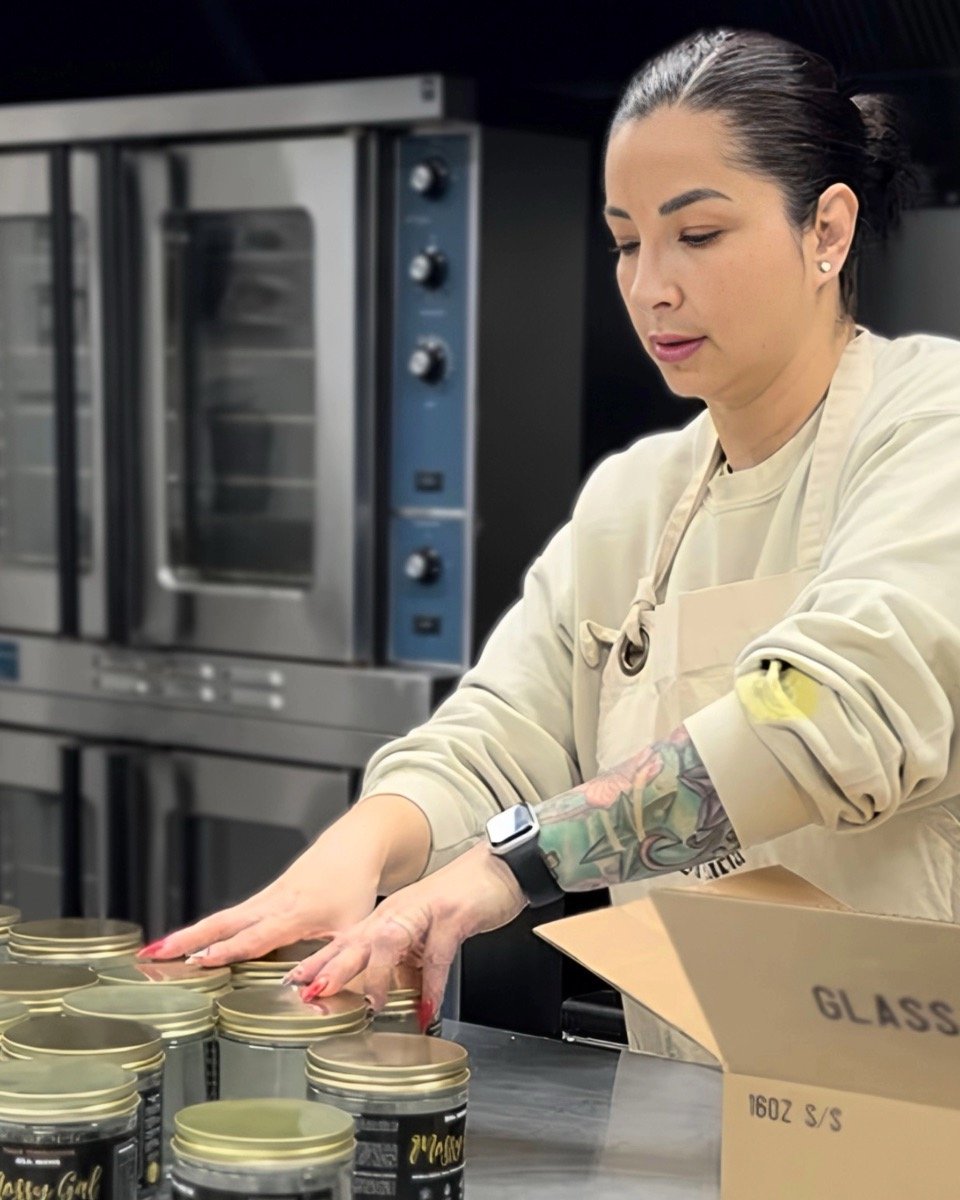Mossy Gal founder Dina arranging jars of sea moss gel in a commercial kitchen.